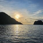 L'isola del Cocco in controluce al tramonto, con una barca da crociera all'ancora sulla destra e il mare calmo