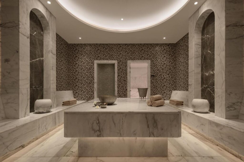 Una sala della spa del JAZ Elite Riviera rivestita di marmo, con un grande tavolo di pietra al centro