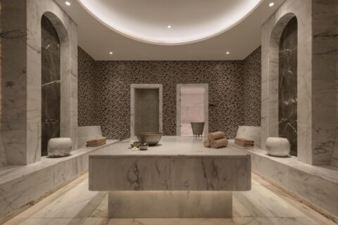 Una sala della spa del JAZ Elite Riviera rivestita di marmo, con un grande tavolo di pietra al centro
