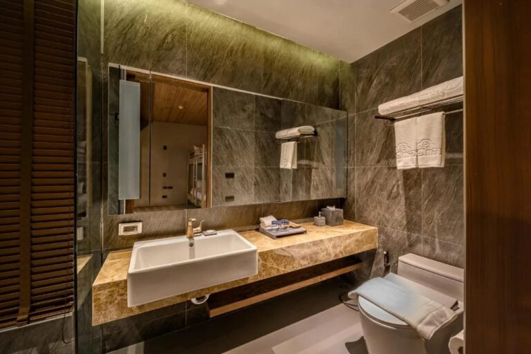 Un bagno in pietra grigia con un lavabo su un piano in marmo e un grande specchio