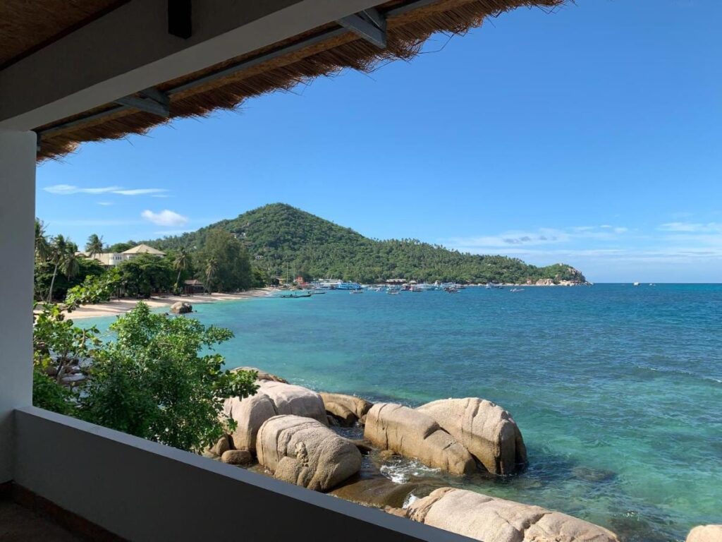 La baia e i suoi scogli visti da una terrazza coperta del Koh Tao Heritage, con barche all'ormeggio