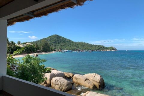 La baia e i suoi scogli visti da una terrazza coperta del Koh Tao Heritage, con barche all'ormeggio