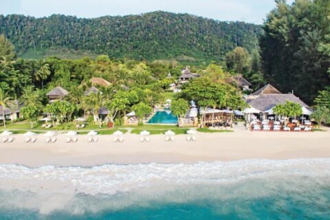 Il Layana Resort visto dal mare, con la spiaggia, gli ombrelloni bianchi, la piscina e i tetti sotto le palme