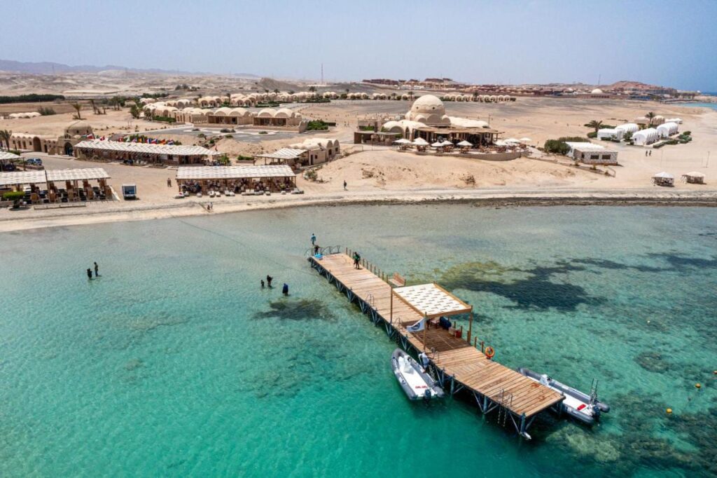 Vista aerea del Marsa Shagra Village, con il pontile, due gommoni e il villaggio in riva all'acqua turchese