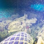 In una stiva buia del Thistlegorm, una moto rovesciata dietro uno pneumatico di camion, illuminata dalla torcia