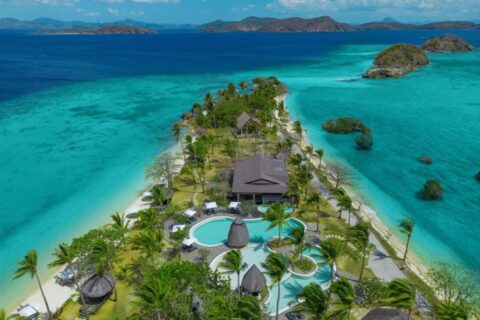 Vista aerea del Two Seasons Coron, con le piscine e le palme su una stretta lingua di terra tra due spiagge
