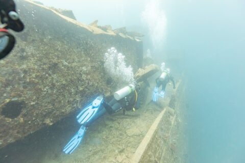 Due sub costeggiano il ponte del Thistlegorm lungo un corridoio, in un'acqua blu lattiginosa